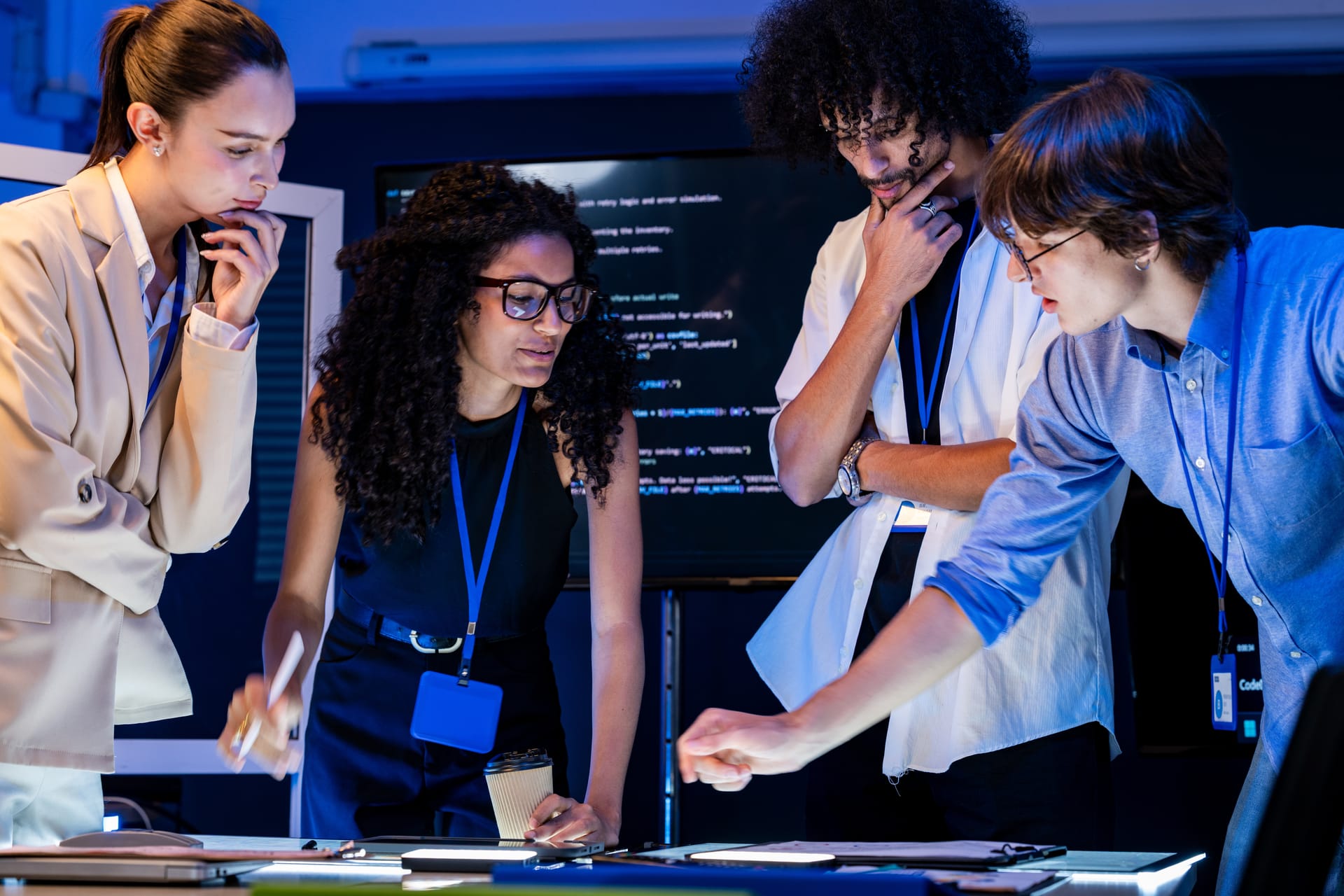 Engineers comparing notes in front of code on large screens